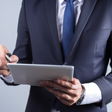 Business person in a suit holding a tablet.